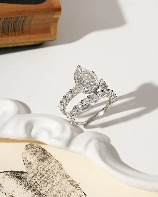 Silver diamond ring on a white surface with a soft shadow